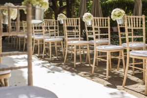 Beach wood chairs with small bouquets of white flowers