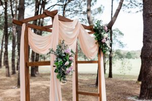 wooden arch with pink draping on woodland setting